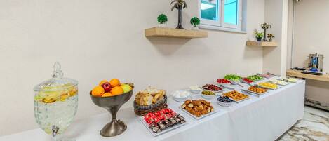Una mesa de buffet con diferentes alimentos y un recipiente de vidrio decorativo.
