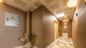 A hallway with marble flooring, a flower arrangement, and a fire alarm panel. - The Business Class Hotel (Istanbul)