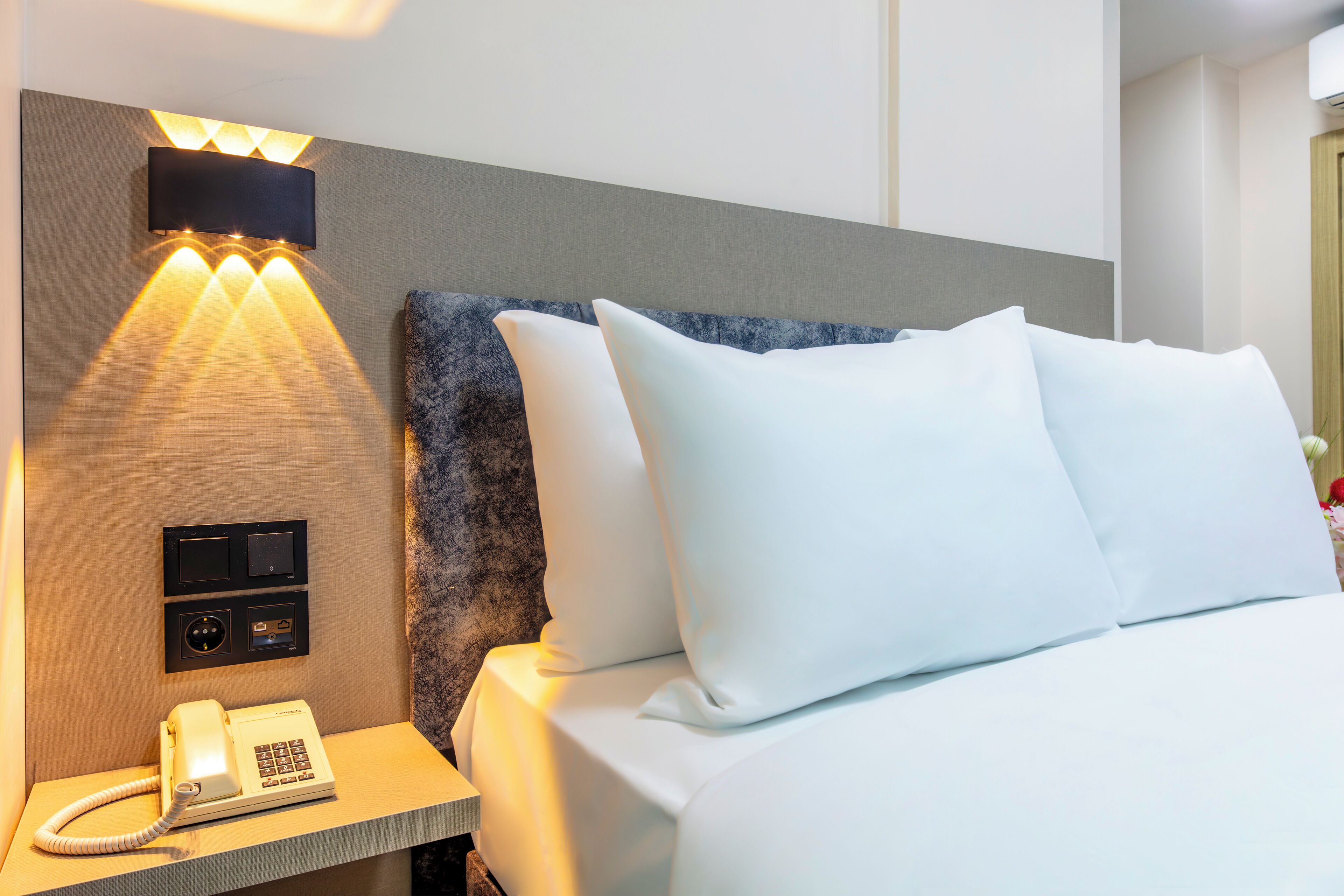 Een hotelkamer met een bed, een bedtelefoon en een aan de muur bevestigde televisie.