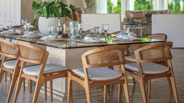 Un espace repas doté d’un plafond en bois, d’un îlot central avec des chaises et offrant une vue sur la verdure environnante.
