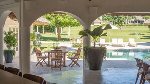 Un espace extérieur abrité, aménagé avec une piscine, des chaises longues et des plantes en pot.