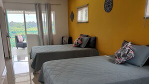 A hotel room with two beds, a balcony with a view, and a yellow accent wall. - La Bella Vista (Calarcá)