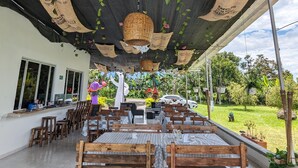 An outdoor dining area with wooden benches and tables, covered by a netted ceiling with hanging baskets. - La Bella Vista (Calarcá)