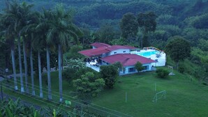 A large house with a red roof, surrounded by lush greenery and palm trees. - La Bella Vista (Calarcá)