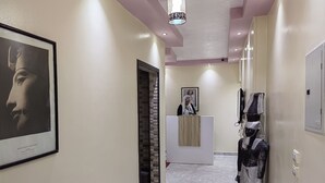 A hallway with a reception desk, a framed artwork, and a statue. - Gem & pyramids Front (Hadayek Al Ahram)