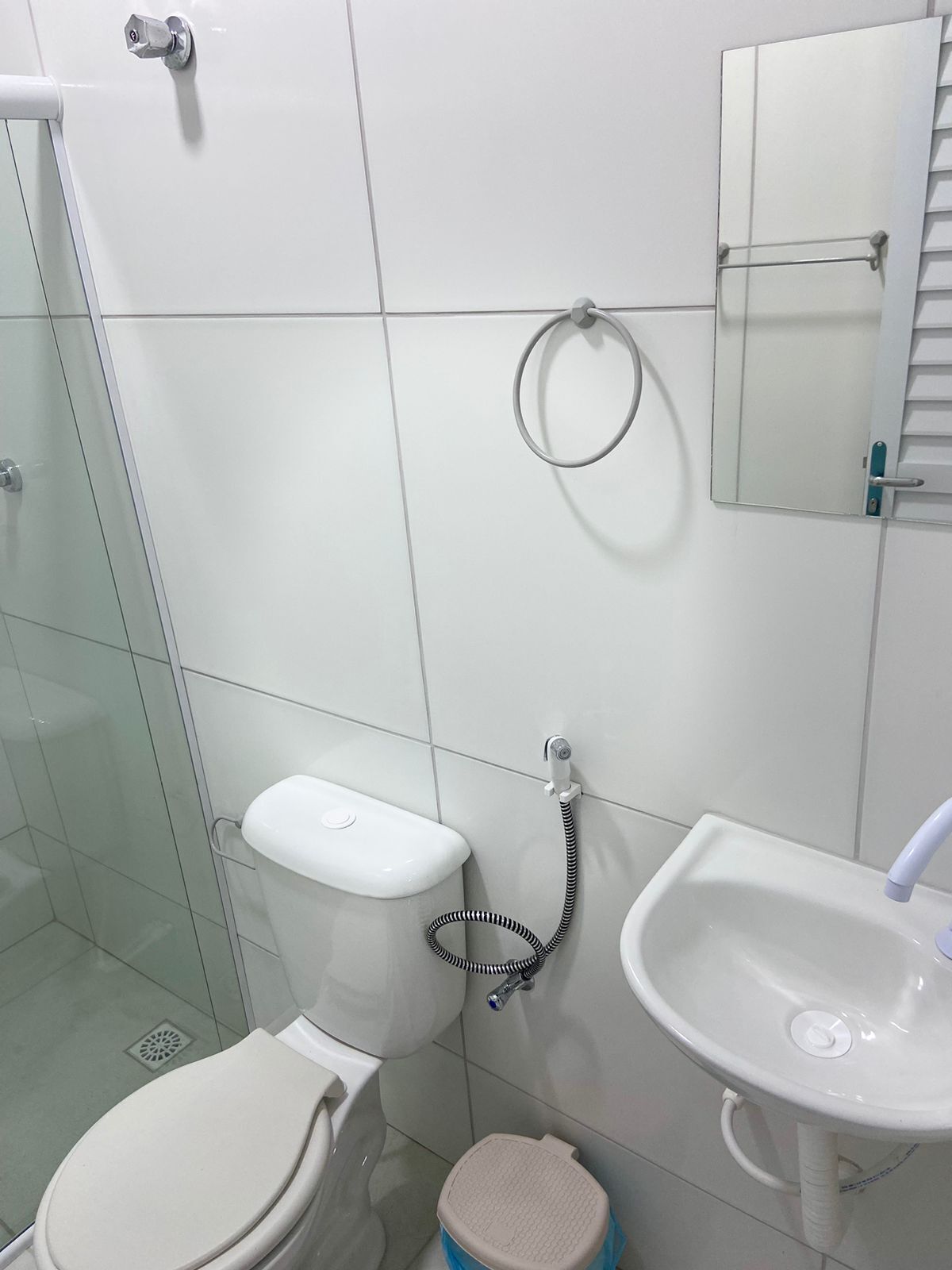Baño con inodoro, lavamanos y cabina de ducha de vidrio.