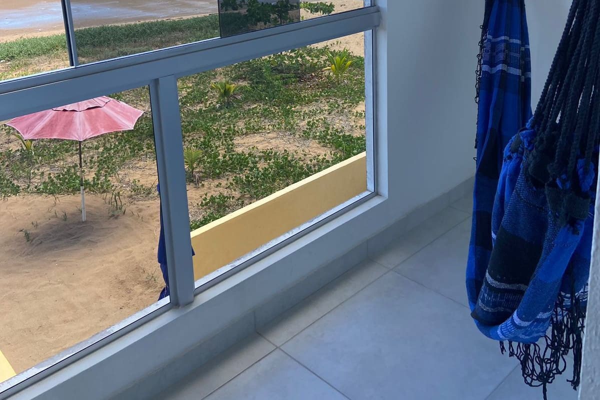 Ein Zimmer mit großem Fenster und Blick auf einen Strand.