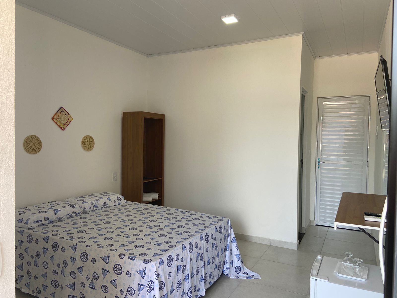 A small, clean room with a bed, a wardrobe, and a door.