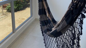 A hammock in a room with a large window overlooking a residential area. - BL Maria Bonita Pousada (Maragogi)
