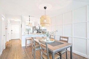A modern kitchen with a central island, wooden dining table, and chairs.