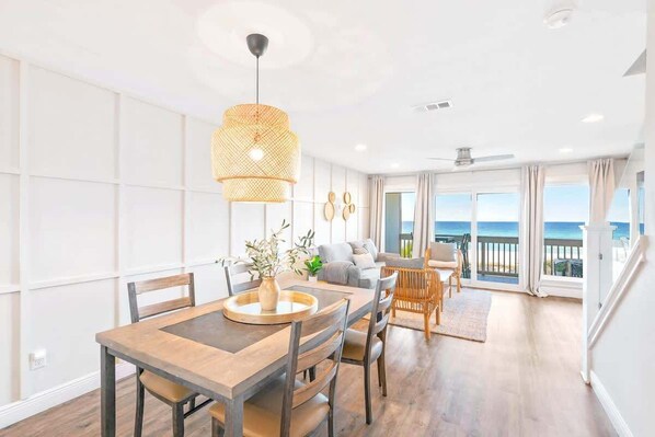 Un salon moderne avec un coin repas, de grandes fenêtres et une vue sur l’océan.