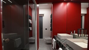 Un bagno moderno con una parete rossa, box doccia in vetro e due lavabi con piastrelle bianche e nere.