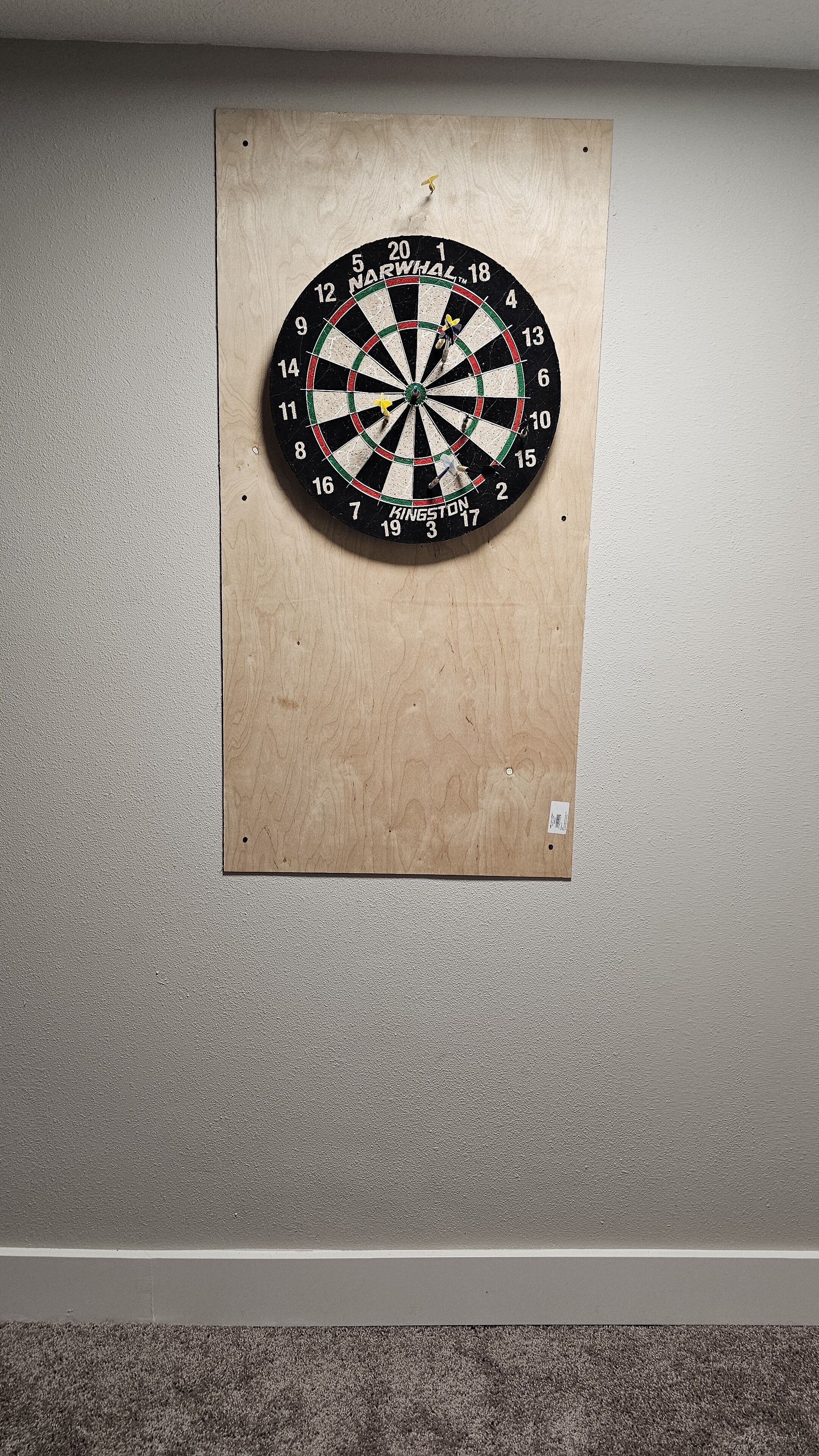 A dartboard mounted on a wooden board against a textured wall.