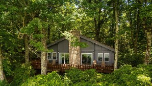 A cabin with a stone chimney, large windows, and a deck with chairs. - Blue Ridge Mountain VIEWS | Pet Friendly | Near Boone & Blowing Rock (Boone)