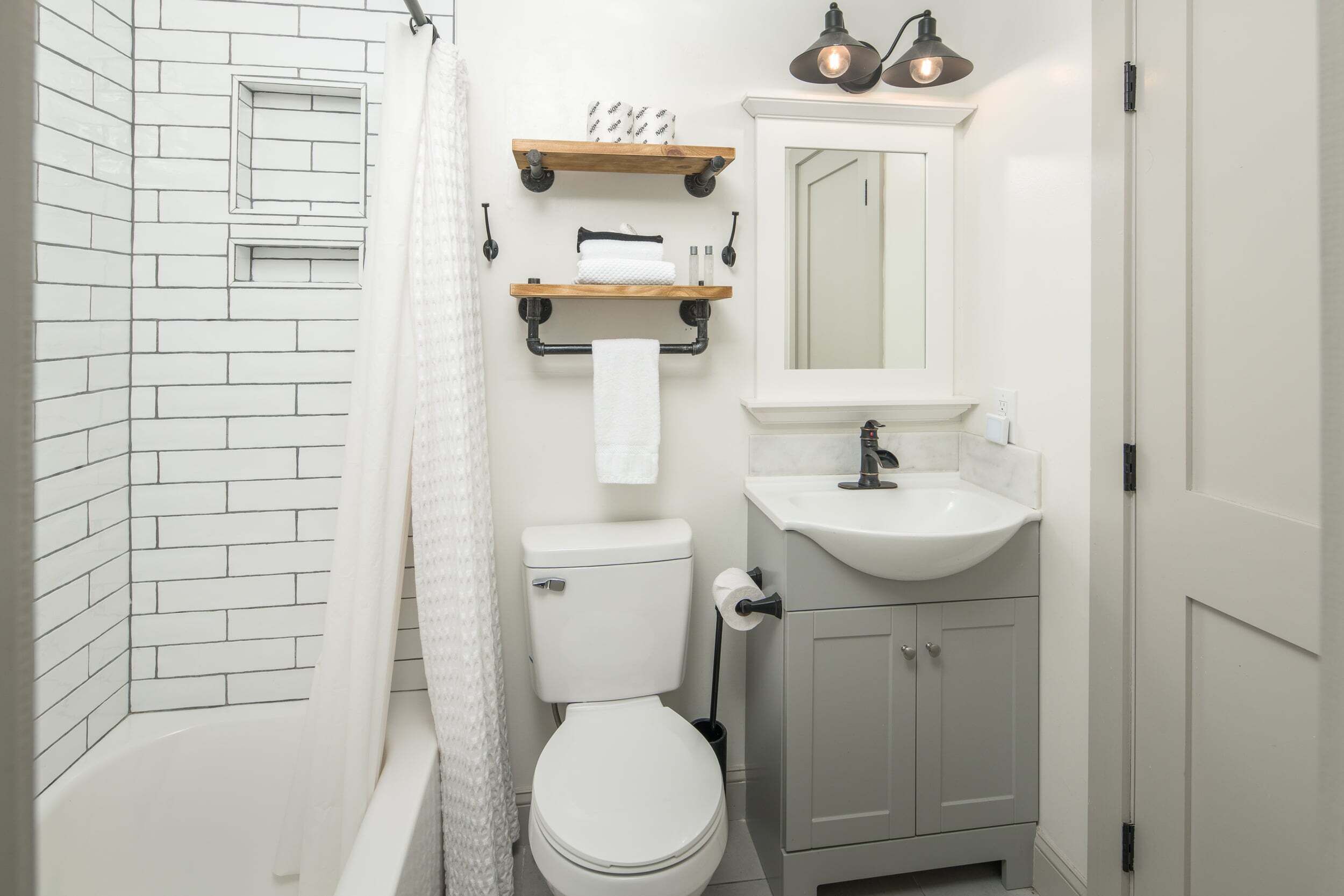 A compact bathroom with a white toilet, a sink, and a shower area.