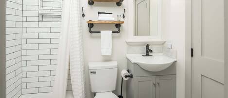 A compact bathroom with a white toilet, a sink, and a shower area.