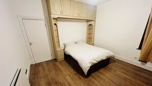 Quarto com cama, piso de madeira, guarda-roupa e radiador.