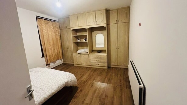 Quarto com cama, soalho em madeira, roupeiro embutido e radiador.