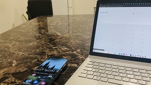 Um laptop sobre uma mesa de mármore, com um smartphone ao lado.
