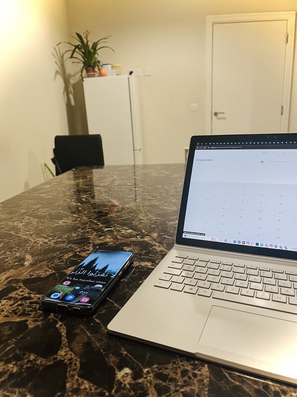 En bærbar computer på et marmorbord med en smartphone ved siden af.