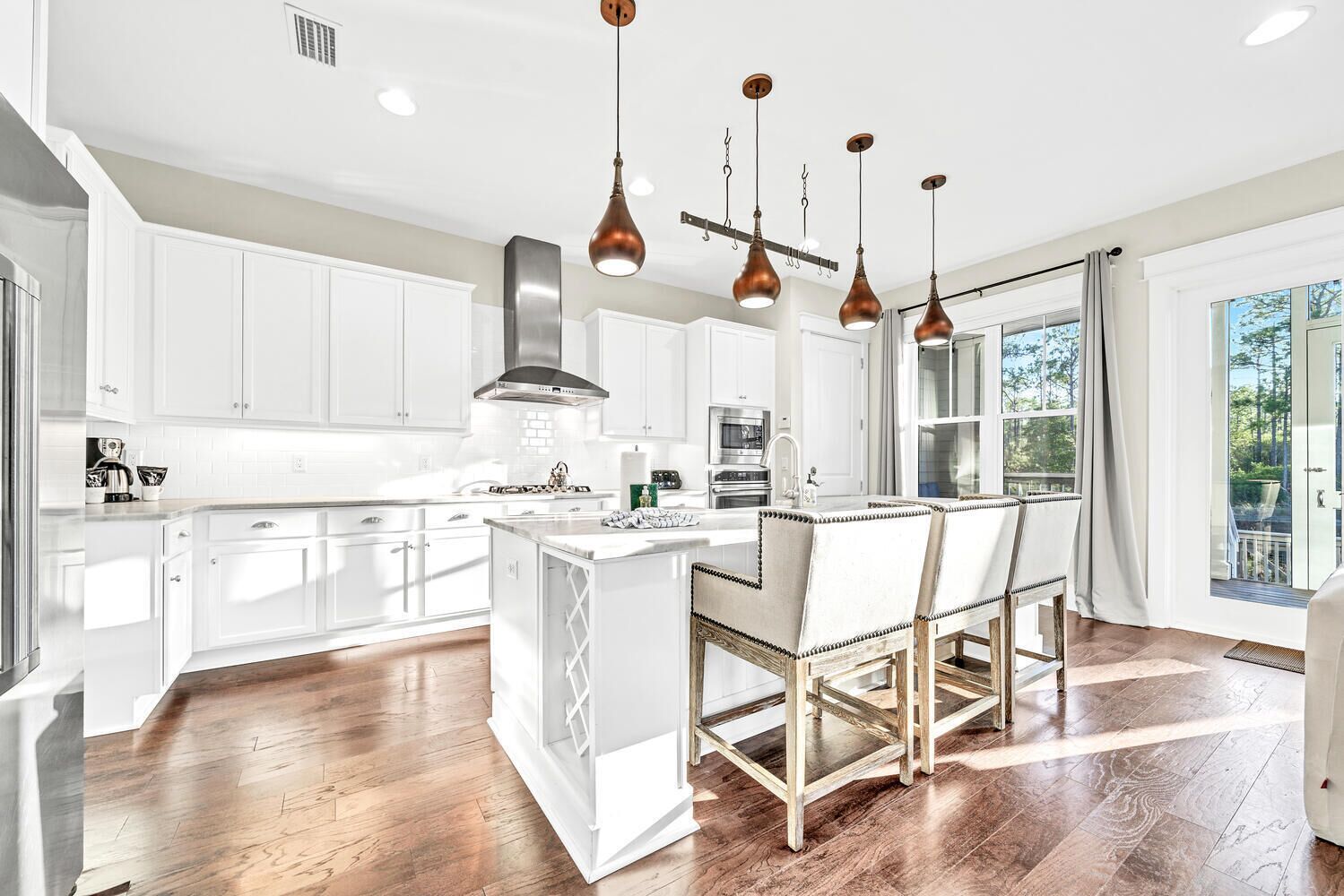 A modern kitchen with white cabinetry, a central island, and pendant lighting.