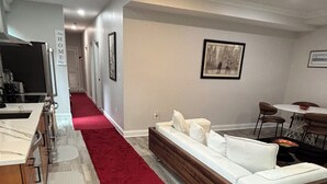 A modern living room with a red carpet, a wooden sofa, and a dining area with a table and chairs.