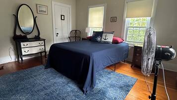 Un dormitorio con cama, cómoda, espejo y un ventilador.