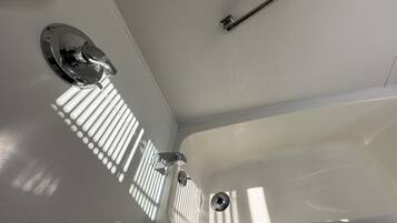 A bathroom with a white sink, a faucet, and a mirror. There is a towel rack on the wall and a bottle of shampoo.