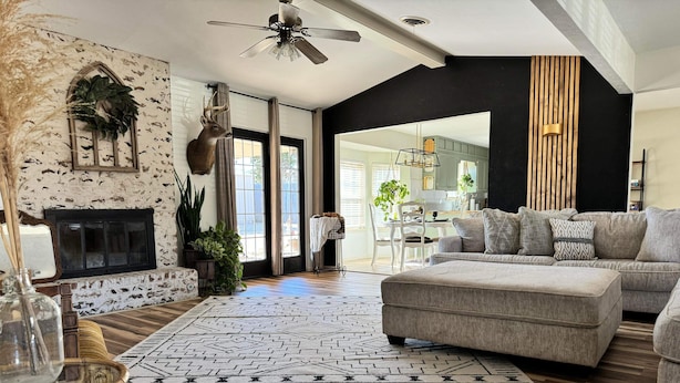A spacious living room with a fireplace, a large sectional sofa, and a dining area visible through an open door.