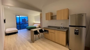 A modern kitchen with wooden cabinets, a stainless steel refrigerator, and a dining area with a bench and chairs. - Hotel Estar (Manizales)