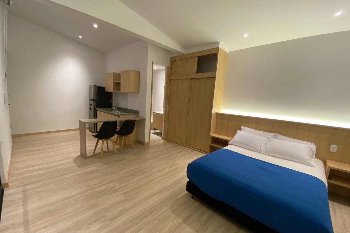 A modern hotel room with a bed, a desk, and a wardrobe.