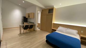 Una habitación de hotel moderna con cama, escritorio y armario.