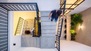 A modern staircase with metal railings and a brick wall with plants. - Hotel Estar (Manizales)