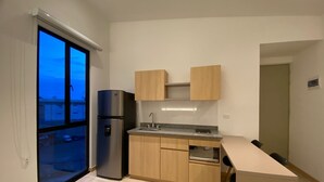 A compact kitchen with wooden cabinets, a stainless steel refrigerator, and a small countertop. - Hotel Estar (Manizales)