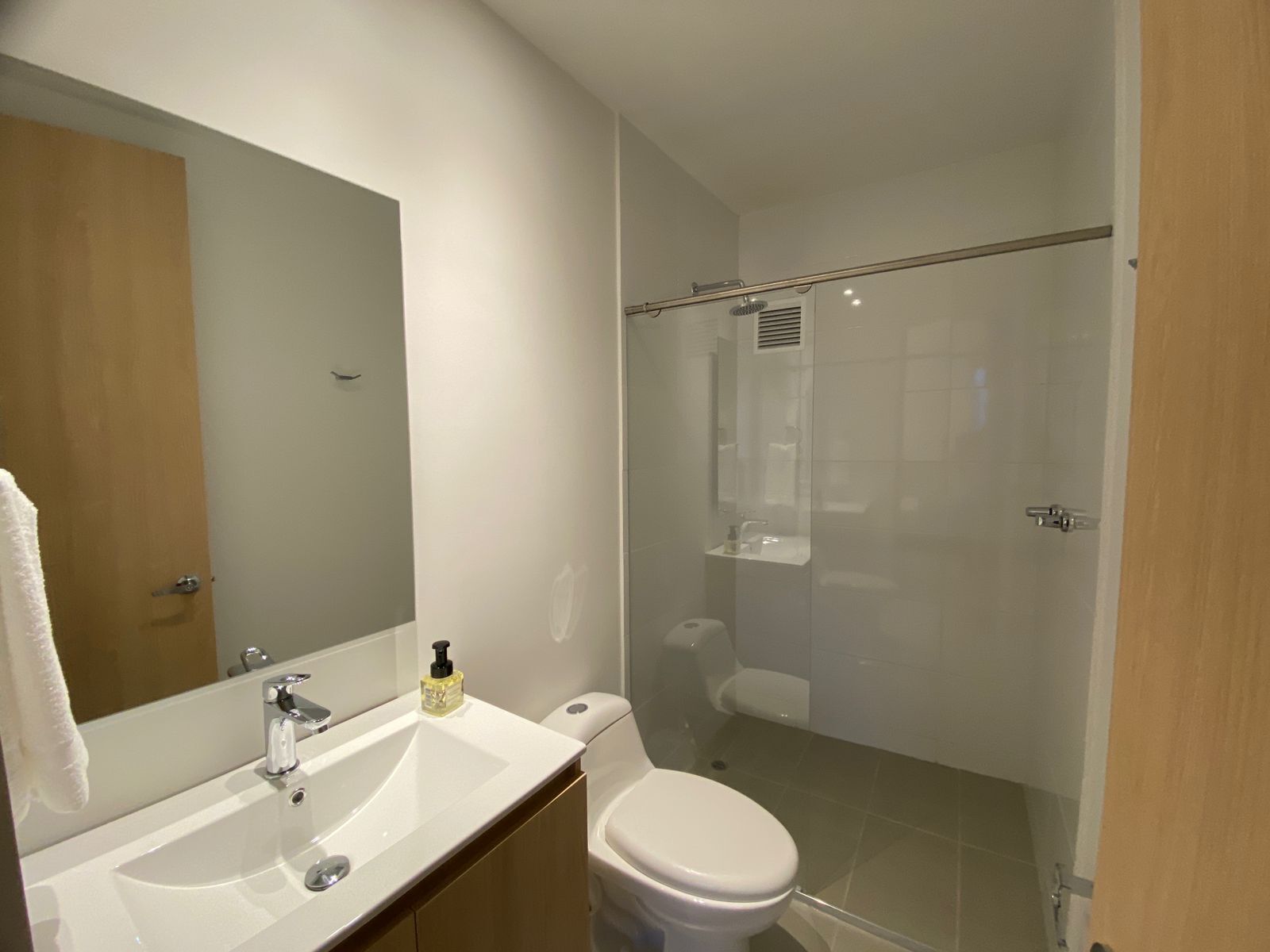 Un baño moderno con lavamanos, espejo y retrete blancos.