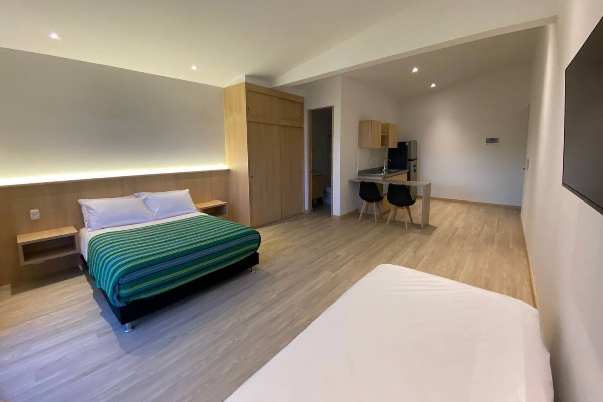 A modern hotel room with a bed, a desk, and a chair.