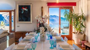 A dining area with a table set for six, a large window with a view of mountains, and a potted plant on the right. - Xino Terrace View by Interhome (Fonteno)