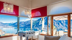 A room with a foosball table, large windows with a mountain view, and a chandelier. - Xino Terrace View by Interhome (Fonteno)