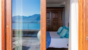 A bedroom with a bed, pillows, and a view of the sea and mountains through a glass door. - Xino Terrace View by Interhome (Fonteno)
