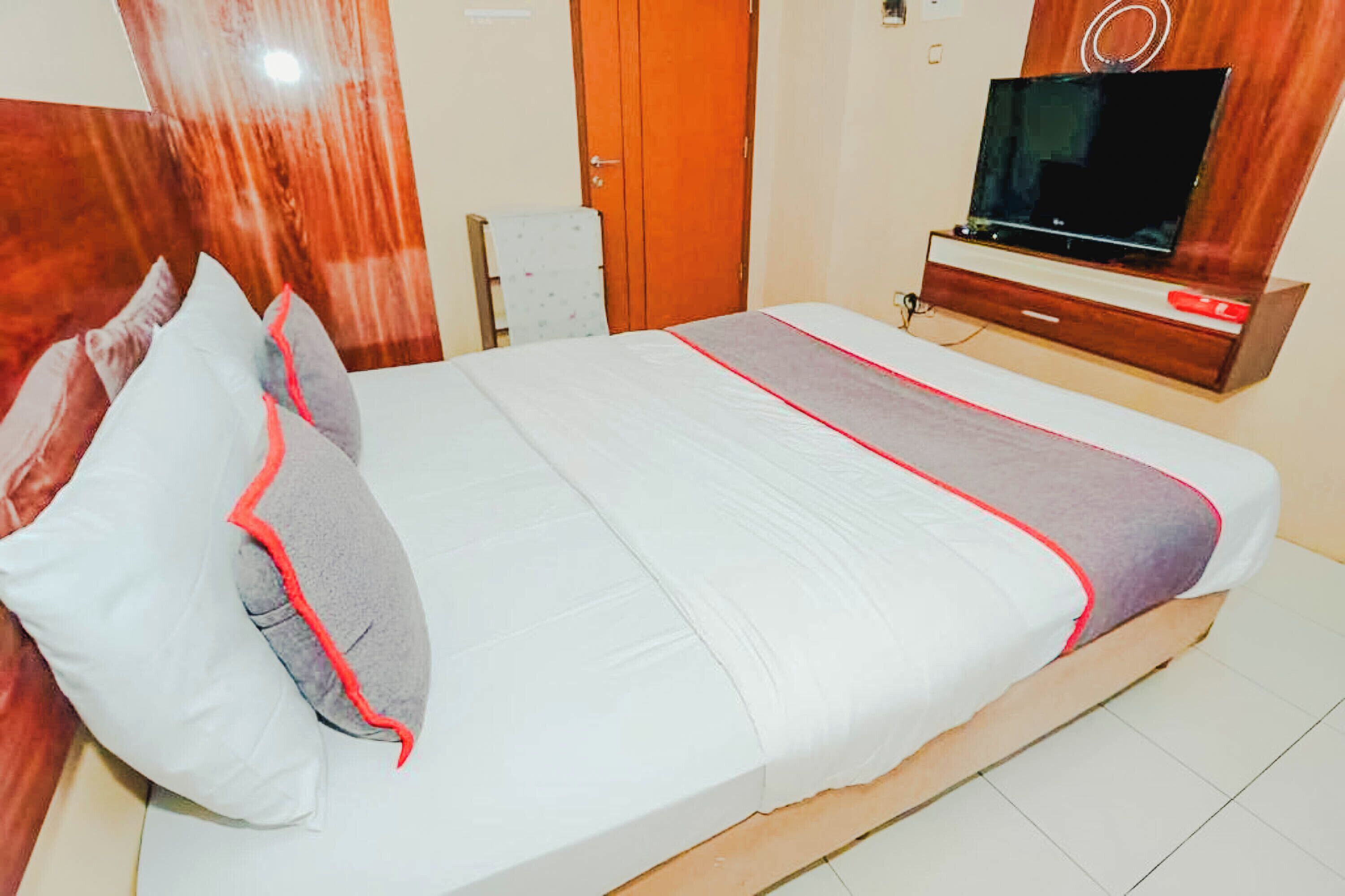 A hotel room with a bed, a TV, and a wooden cabinet.