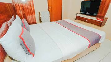 A hotel room with a bed, a TV, and a wooden cabinet.