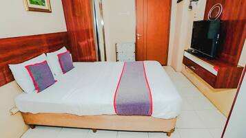 A hotel room with a large bed, wooden headboard, a television, and a wardrobe.