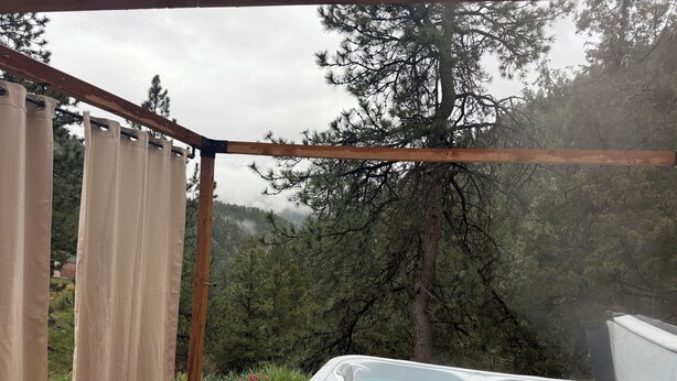 A hot tub with a wooden deck and a view of a forested area. - Views, Rafting, Skiing, Tubing, Casinos, Zipline, Hiking, EV, Hot Tub (Idaho Springs)
