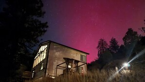 A house with a large window, a balcony, and a view of the night sky. - Views, Rafting, Skiing, Tubing, Casinos, Zipline, Hiking, EV, Hot Tub (Idaho Springs)