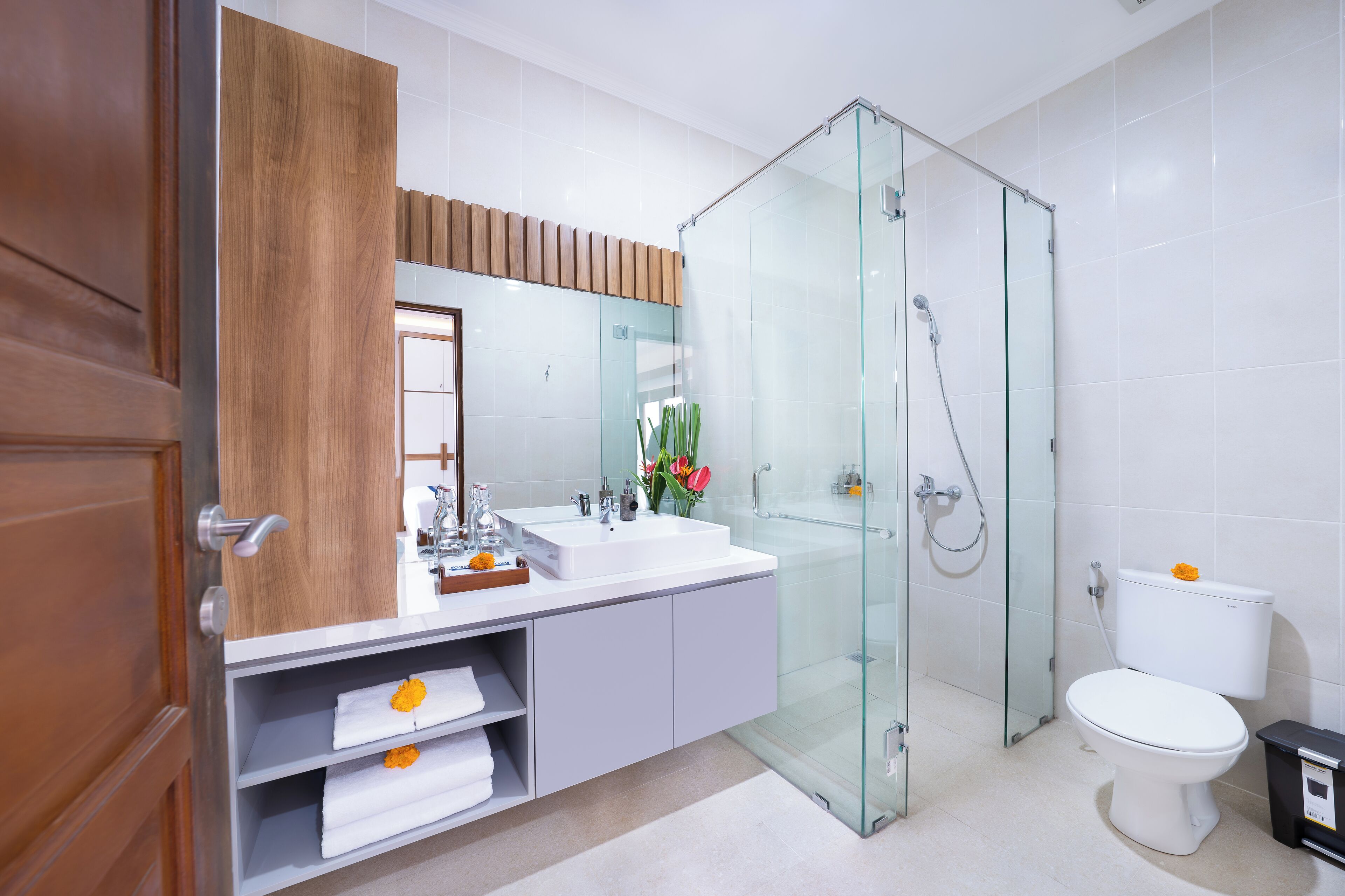 Un baño moderno con cabina de ducha de vidrio, un lavabo blanco y un inodoro.