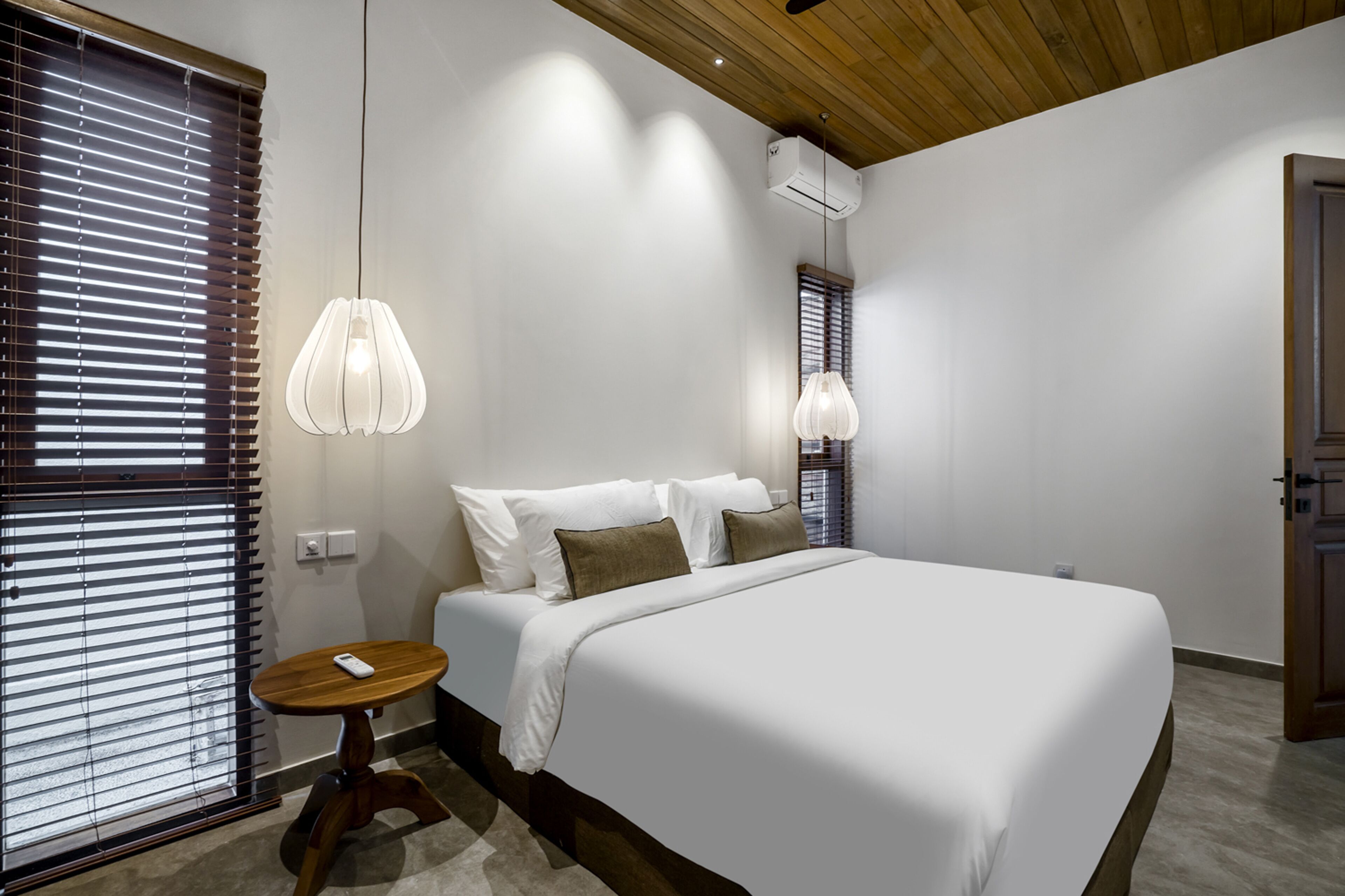 Une chambre moderne avec un grand lit, un plafond en bois et une petite table ronde.