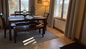 Un comedor con una mesa de madera, sillas, un pequeño árbol de Navidad y una lámpara.