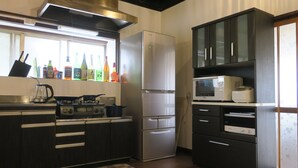 A modern kitchen with dark cabinetry, a stainless steel refrigerator, a microwave, and a gas stove. - 5 minutes from Azumino Interchange! Ideal for families and groups staying together! A private old house that can accommodate up to 14 people in 5 bedrooms! Barbecue available on the terrace! (AZUMINO-CITY TOYOSHINA TAZAWA)