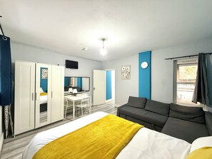 A hotel room with a bed, a desk, a sofa, and a wardrobe.