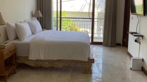 A bedroom with a bed, a nightstand, a TV, and a balcony with curtains. - Soleil Suites Petitenget By the jero 18 (Keroboken Kelod)